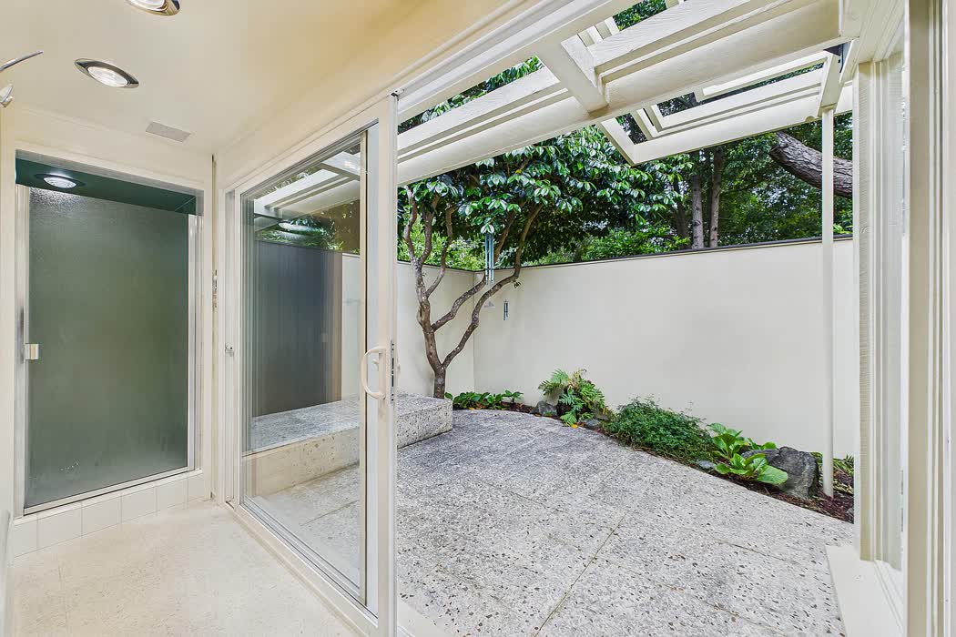 A glazed corridor opening onto a small planted atrium open to the sky.