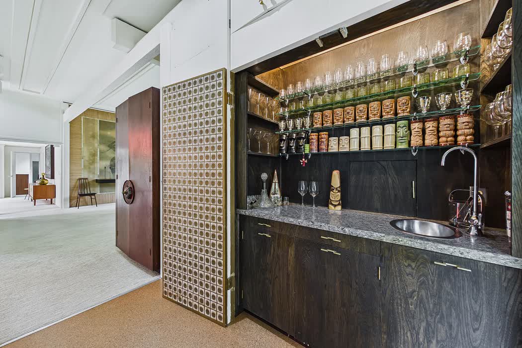 A concealed wet bar in dark timber behind a pierced screen.