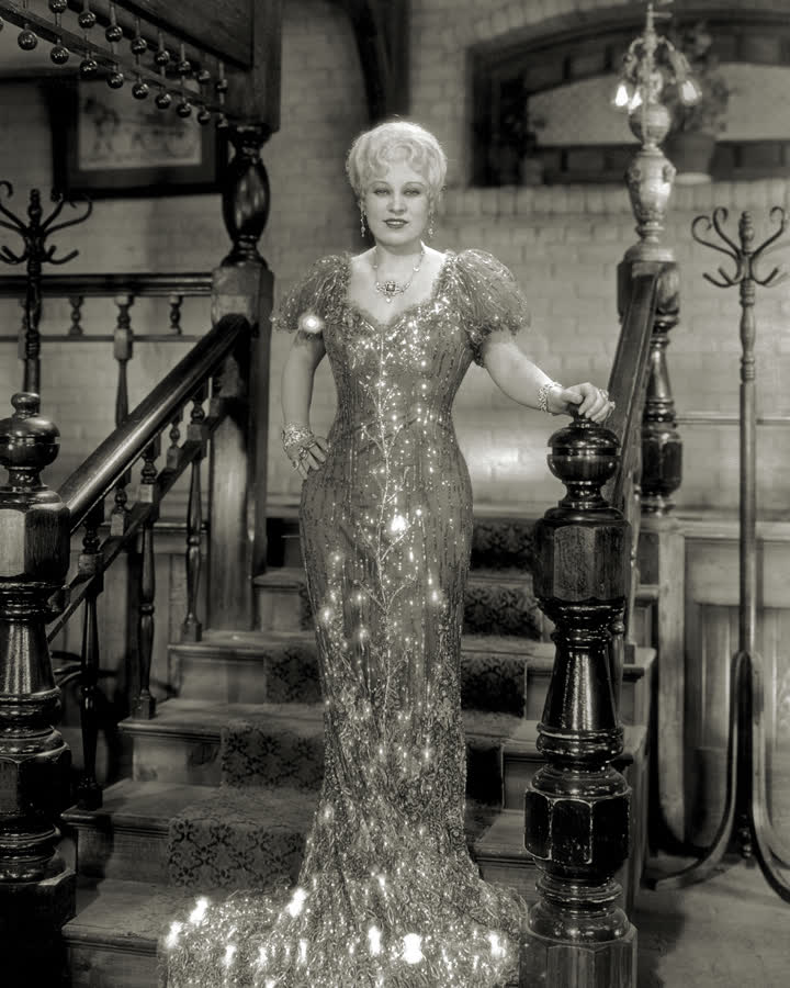 Mae West in a beaded gown on an ornate Victorian staircase, from She Done Him Wrong.